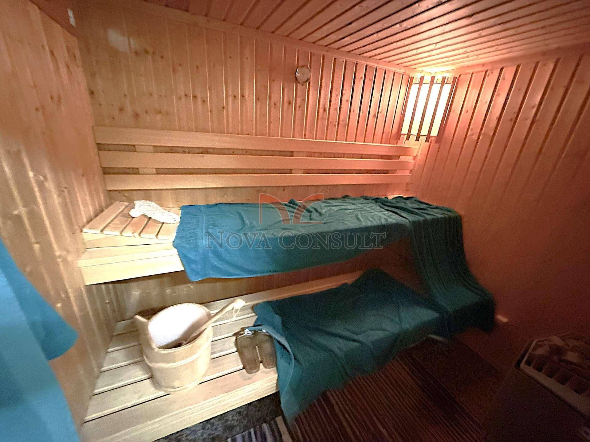 Traditionelle Holzsauna mit Bänken und Eimer für Aufgüsse.
