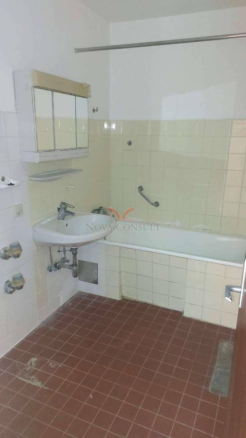 Badezimmer mit Badewanne, Waschbecken und Spiegelschrank, ausgestattet mit Haltegriff.