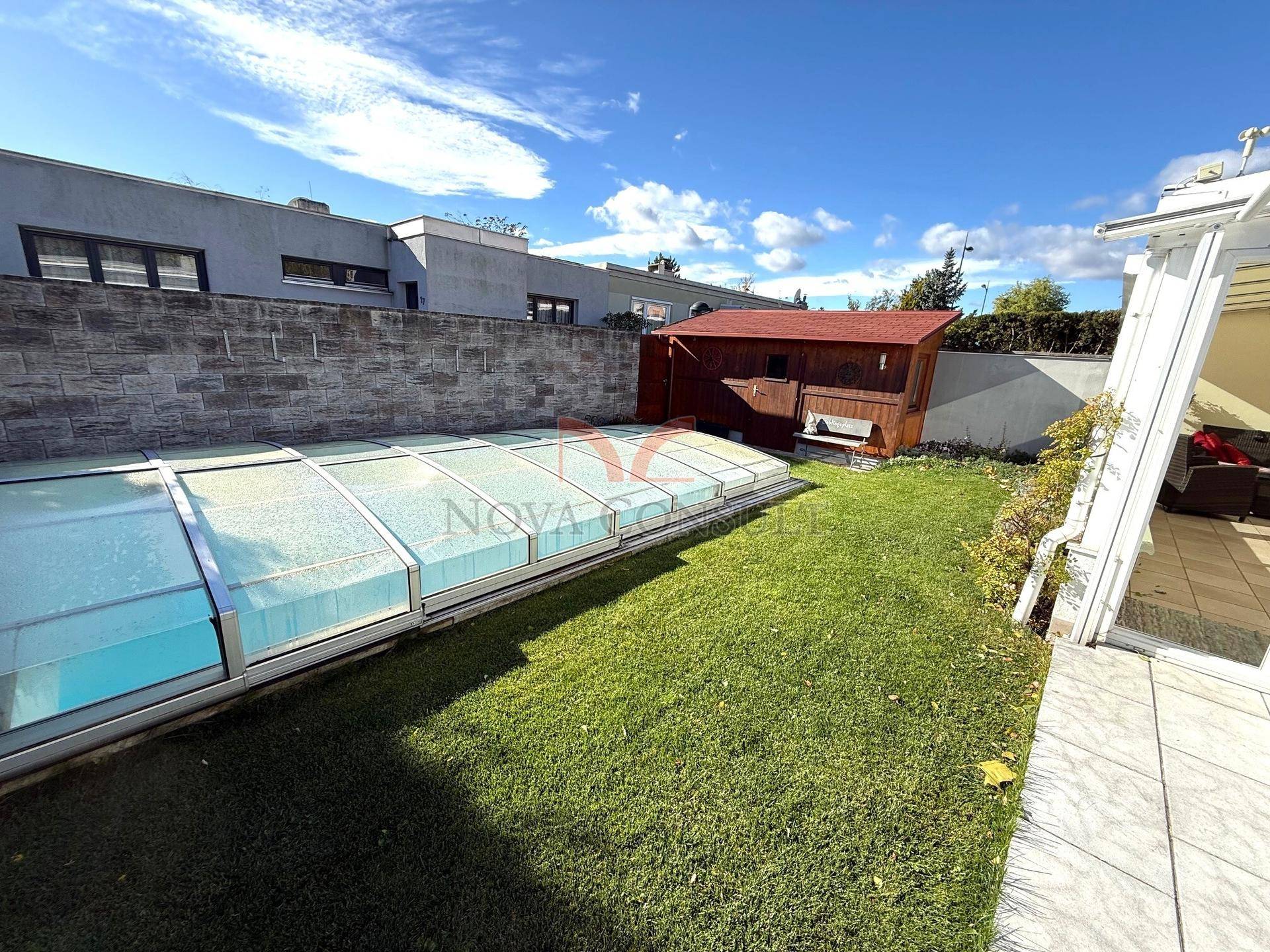 Gepflegter Garten mit überdachtem Pool, Rasenfläche und einem kleinen Holzschuppen.