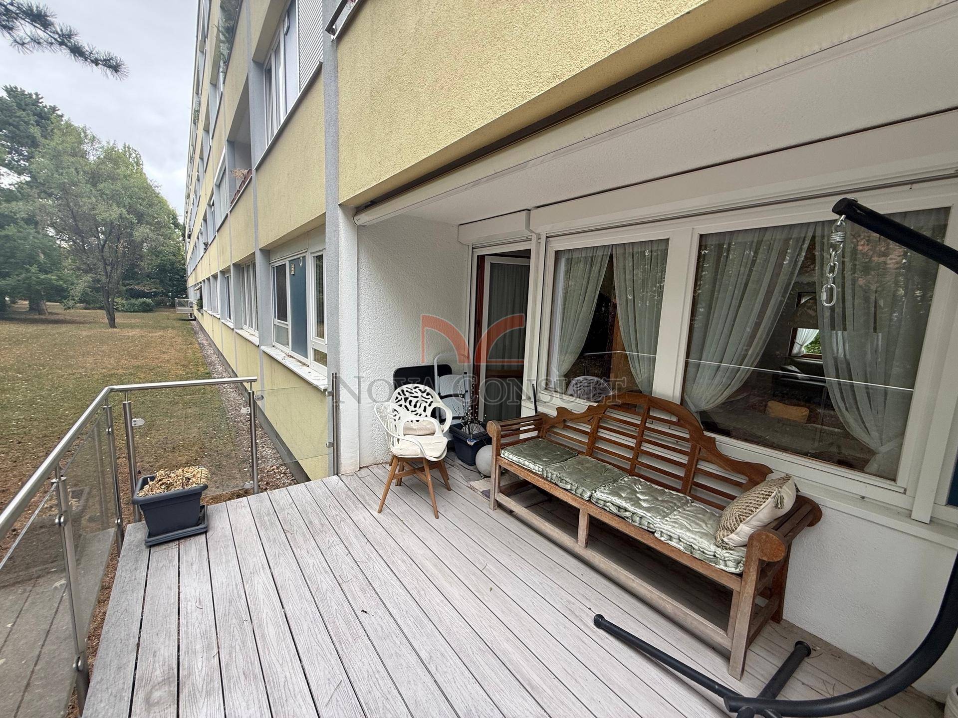 Geräumige Holzterrasse mit Sitzbank und Blick ins Grüne, ideal zum Entspannen im Freien.