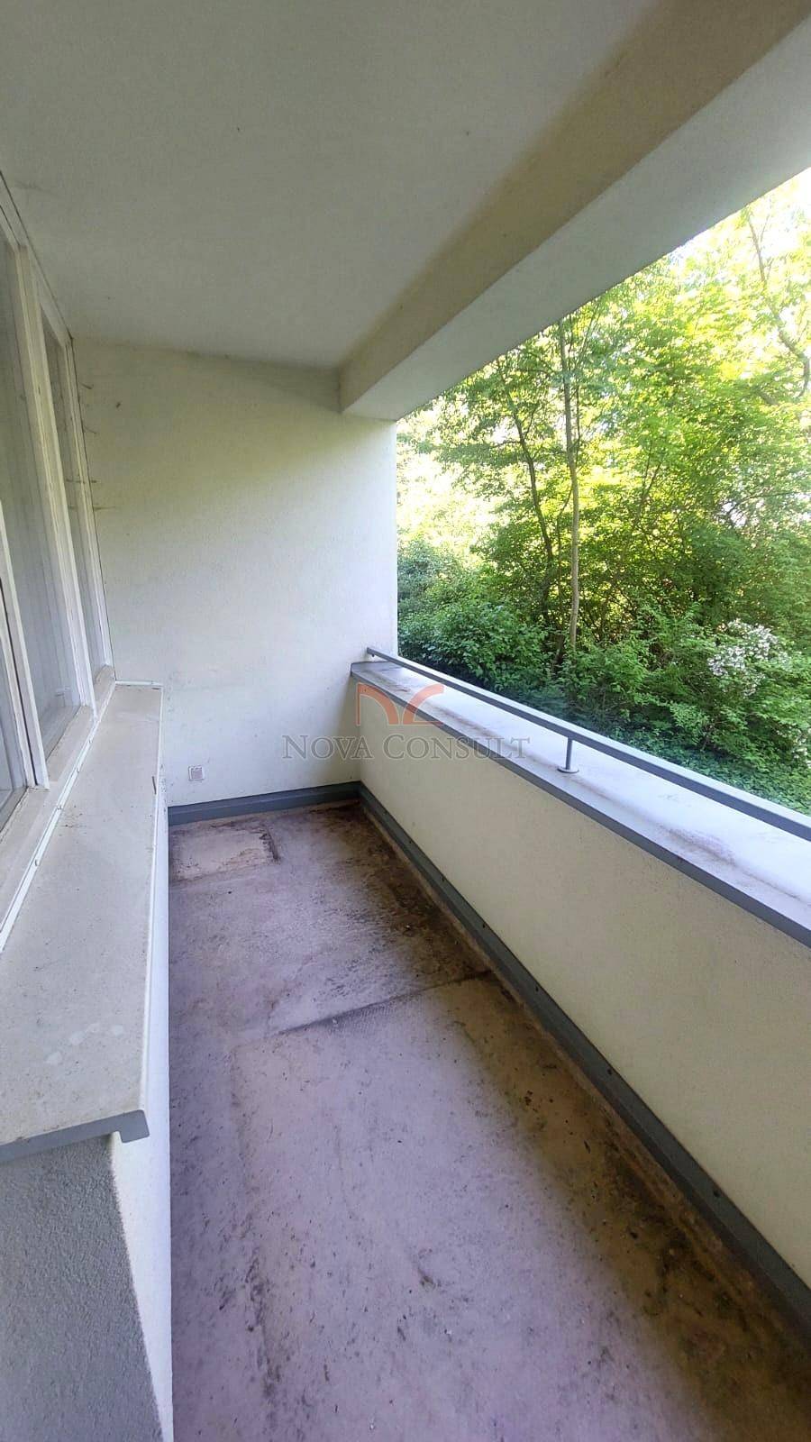 Schmaler Balkon mit Blick ins Grüne und einfacher Brüstung.
