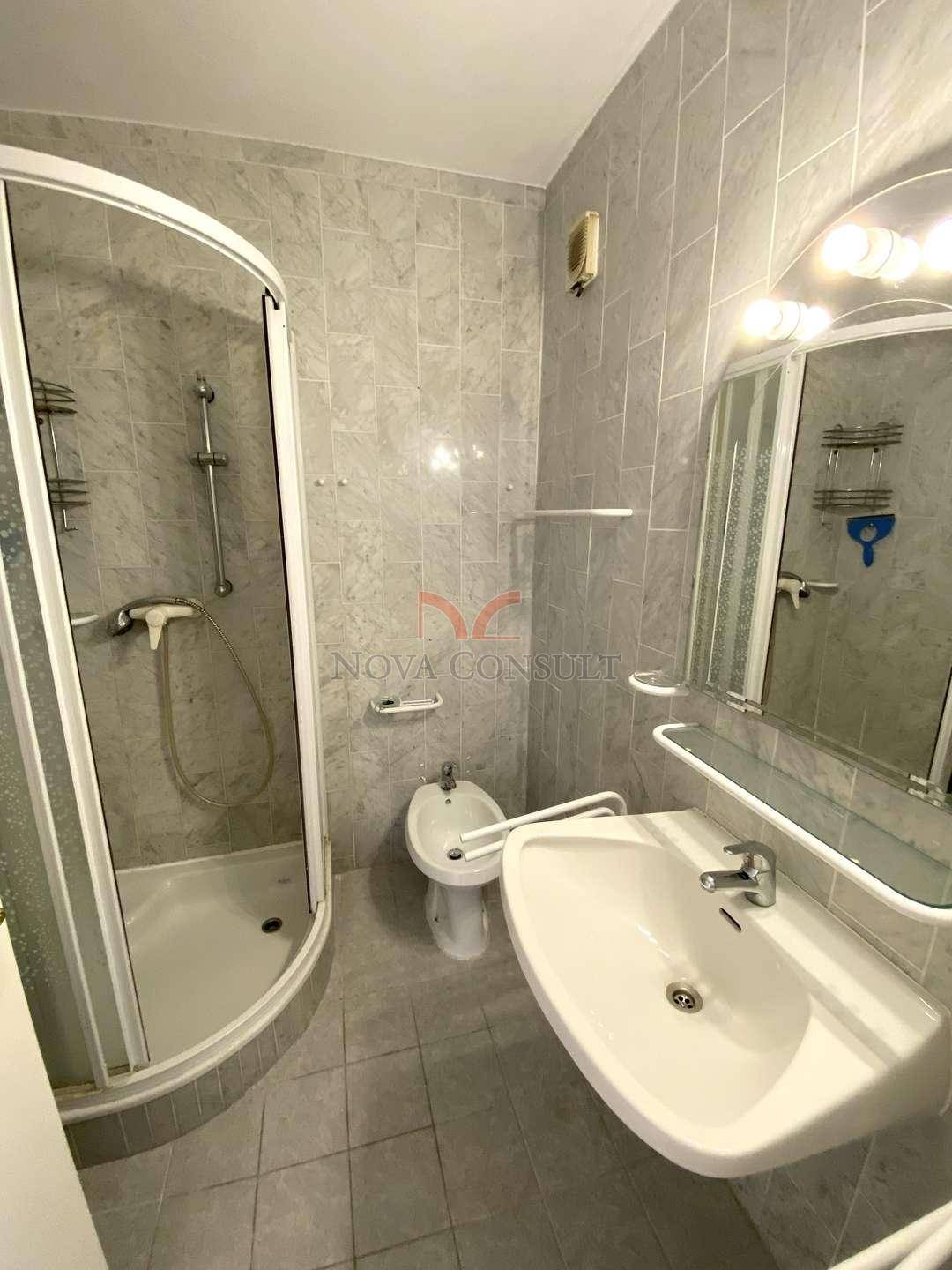 Gefliestes Badezimmer mit Dusche, Waschbecken, Bidet und Spiegelschrank.