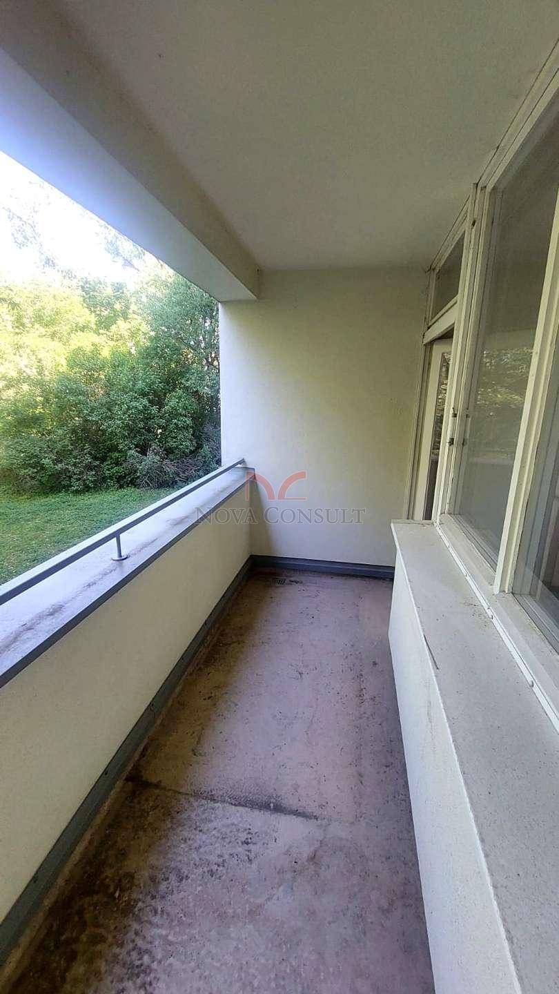 Langer Balkon mit Betonboden und Ausblick auf die umliegende grüne Landschaft.