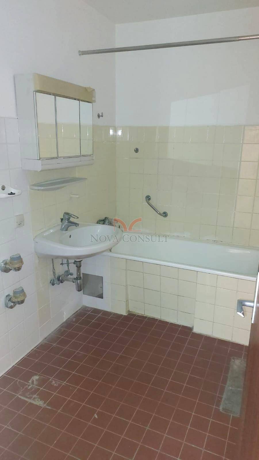 Badezimmer mit Badewanne, Waschbecken und Wandfliesen im Stil der 80er Jahre.