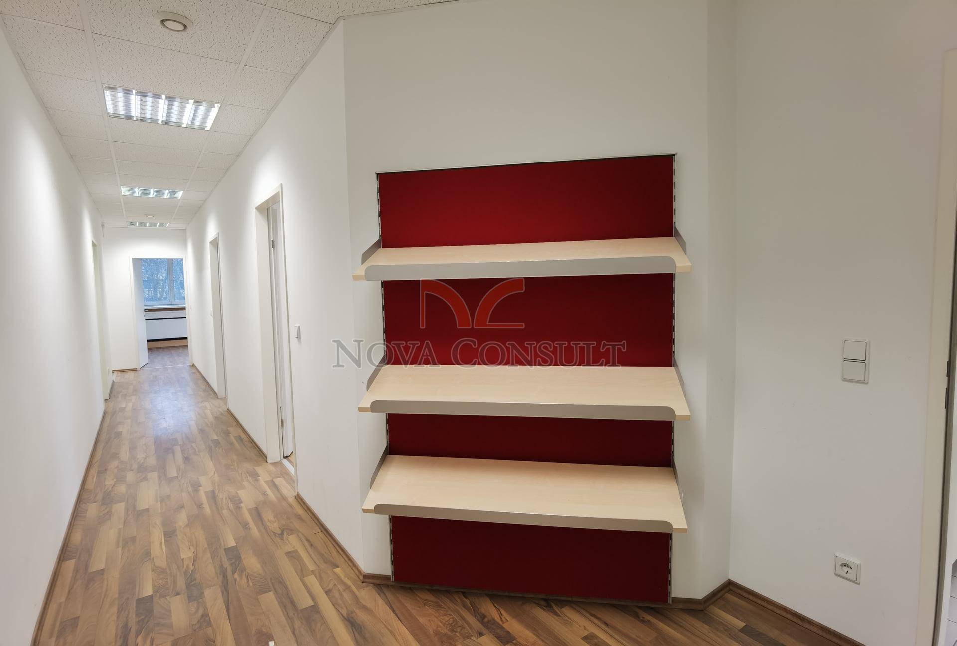 Heller Flur mit Holzboden und einer roten Akzentwand, ausgestattet mit praktischen Holzregalen.