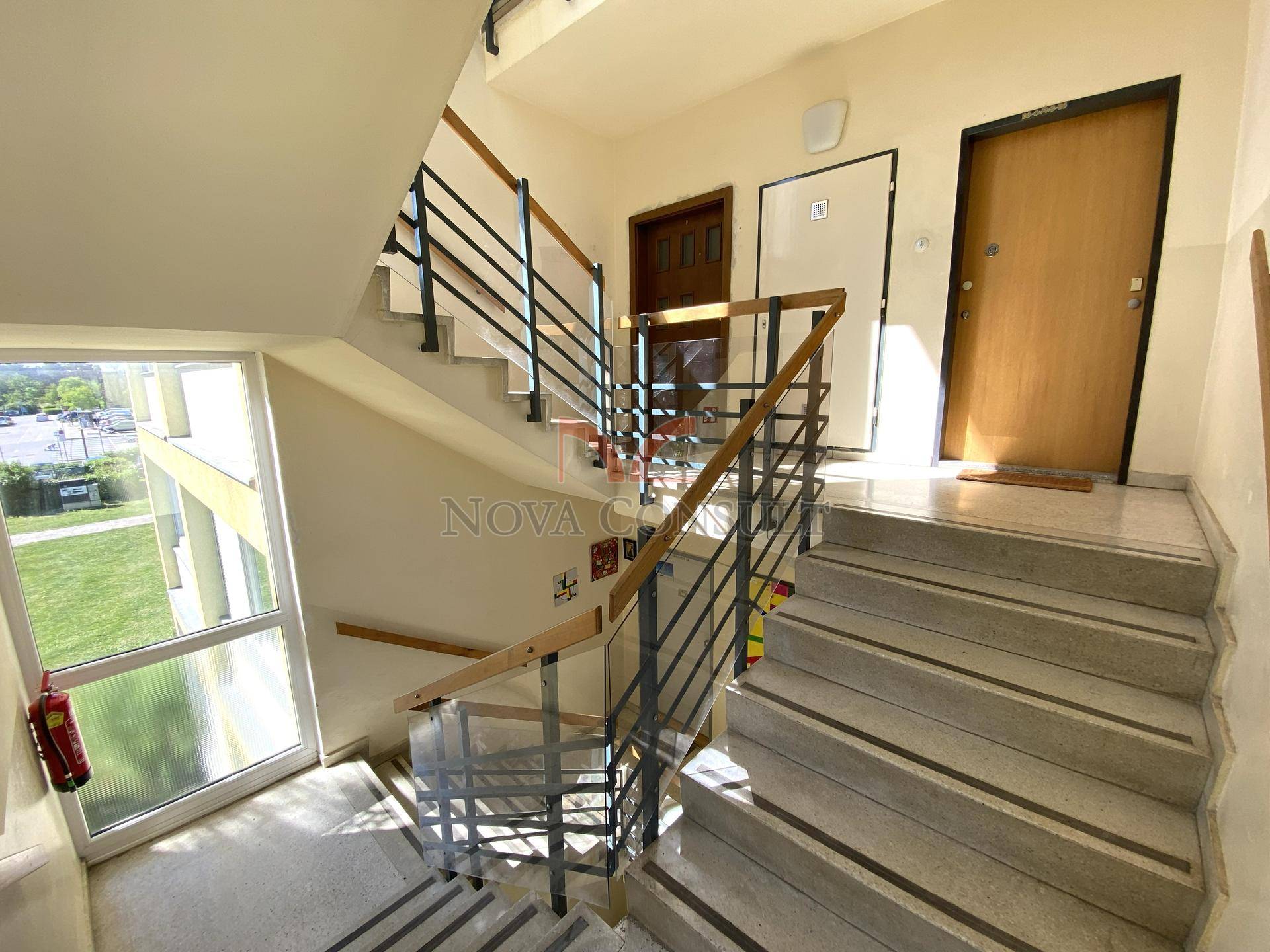 Treppenhaus mit Marmorstufen, Metallgeländer und großen Fenstern für viel Tageslicht.