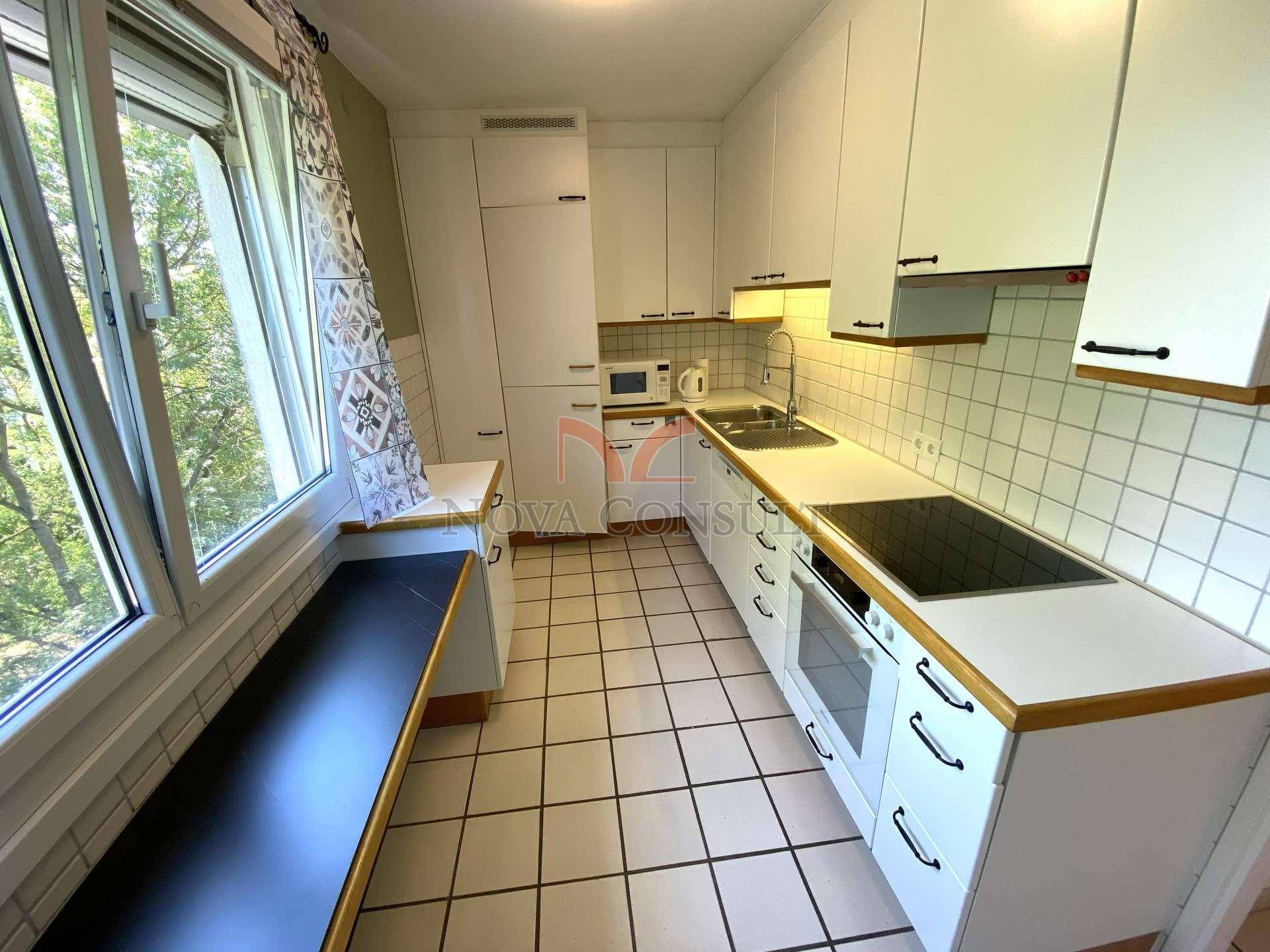 Funktionale Küche mit weißen Schränken, Fliesenboden und Fenster mit Ausblick.