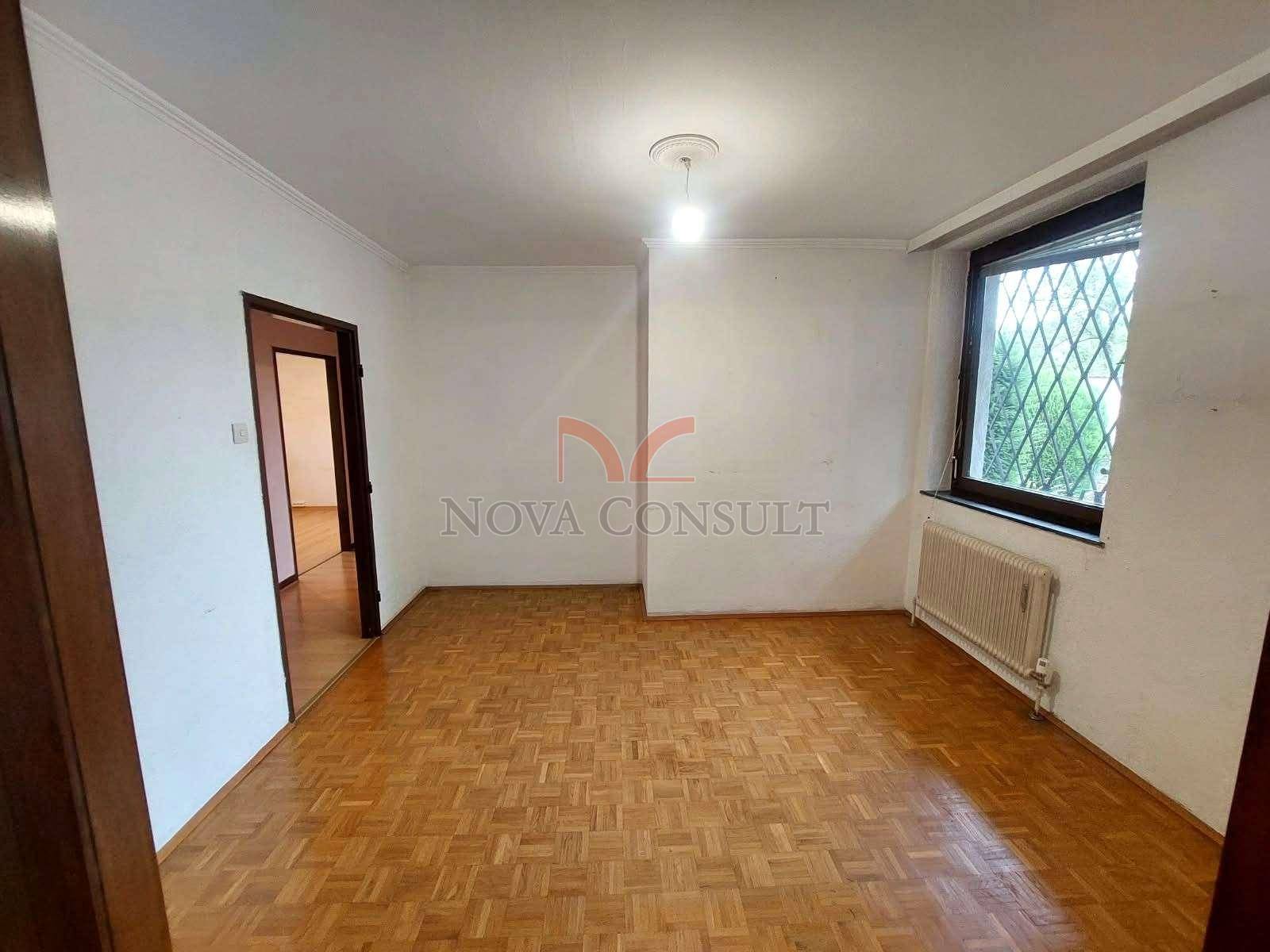 Helles Zimmer mit Parkettboden und einem Fenster, das viel Tageslicht hereinlässt.