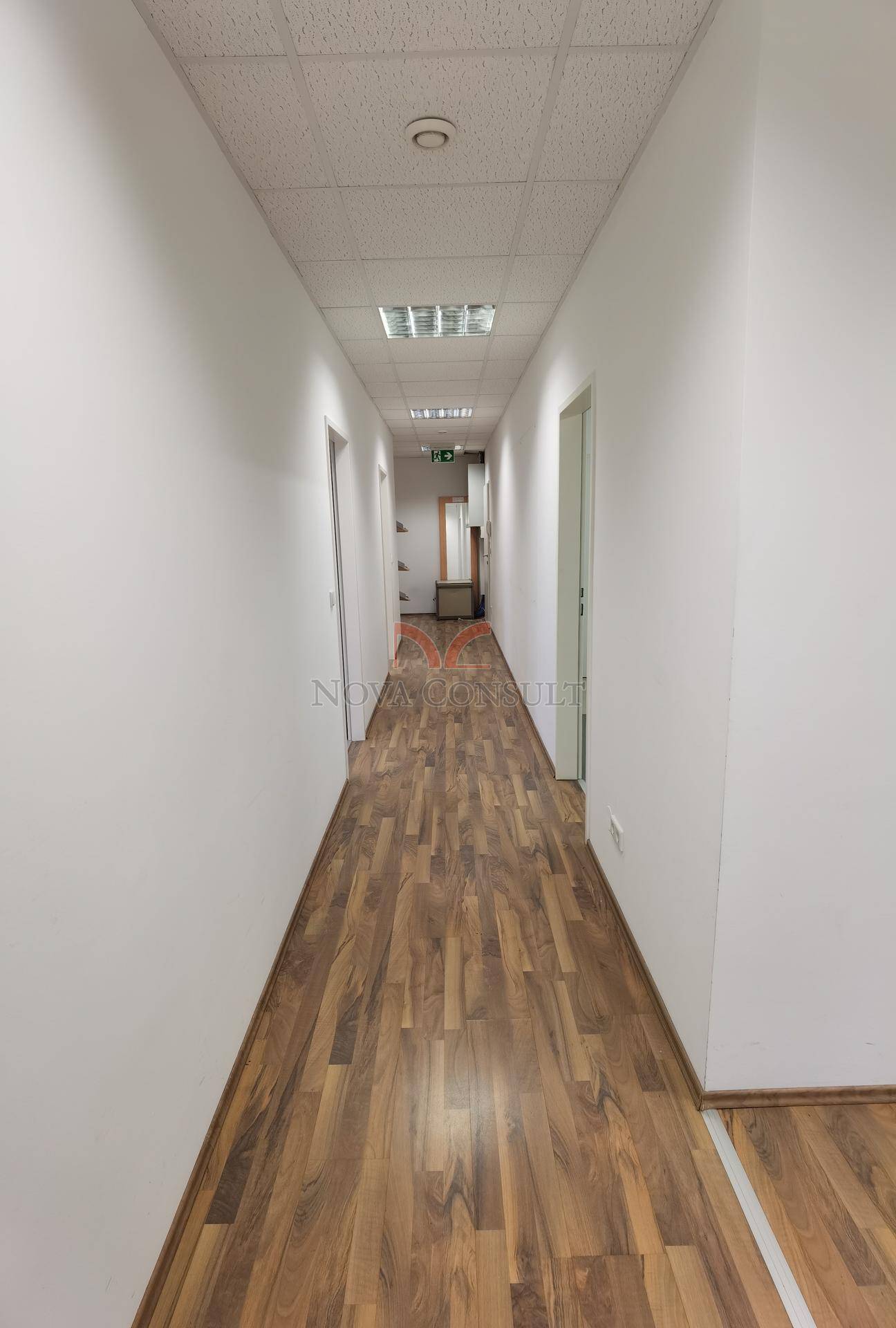 Langer Flur mit Holzboden und Türen, die zu verschiedenen Büroräumen führen.
