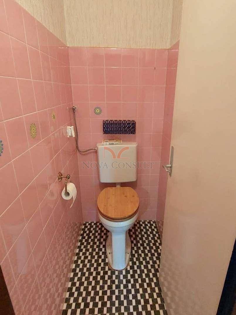 Separate Toilette mit rosa Fliesen an den Wänden und gemustertem Boden.