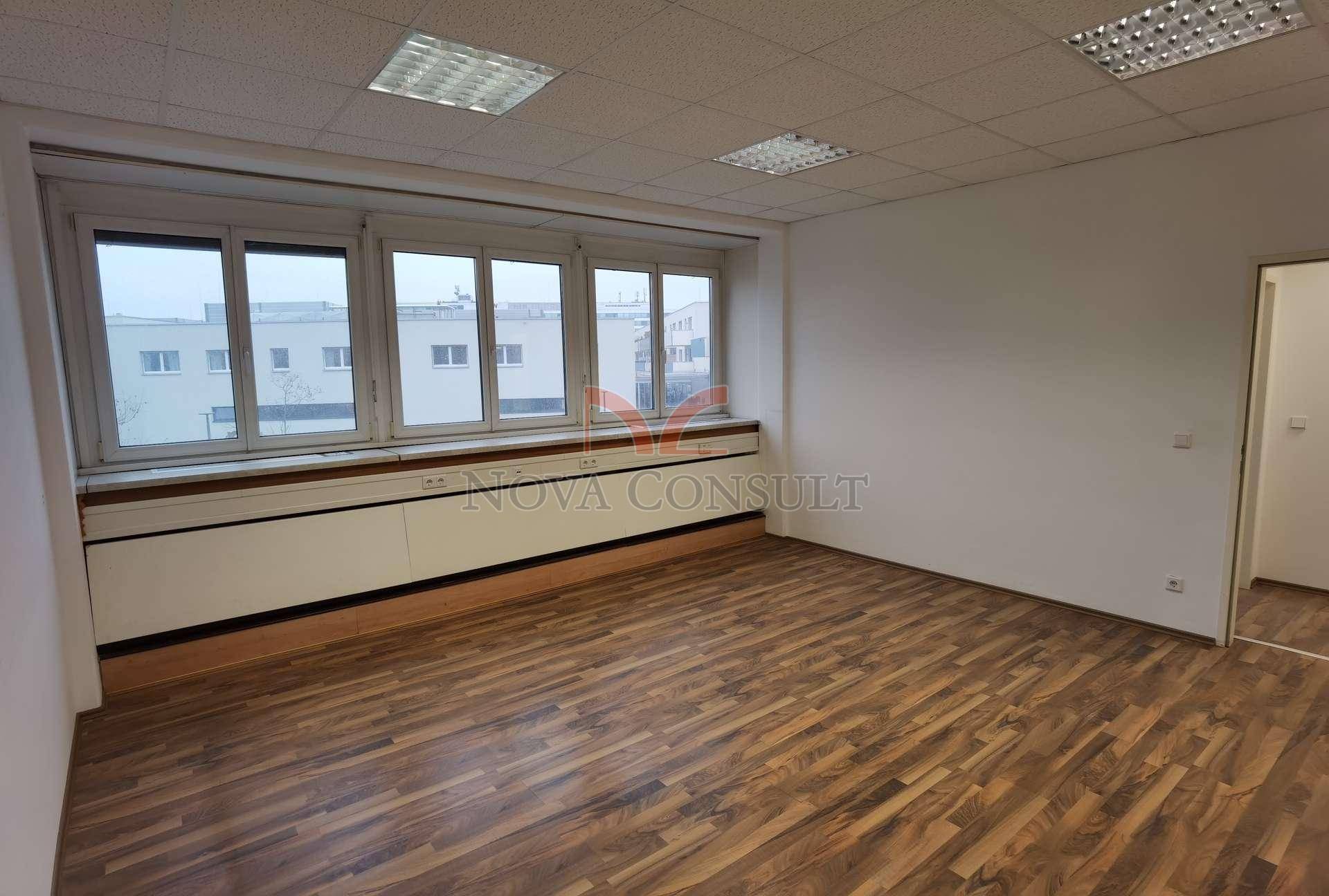 Leeres Büro mit Holzboden und Fenstern, die einen weiten Blick auf die Stadtlandschaft ermöglichen.