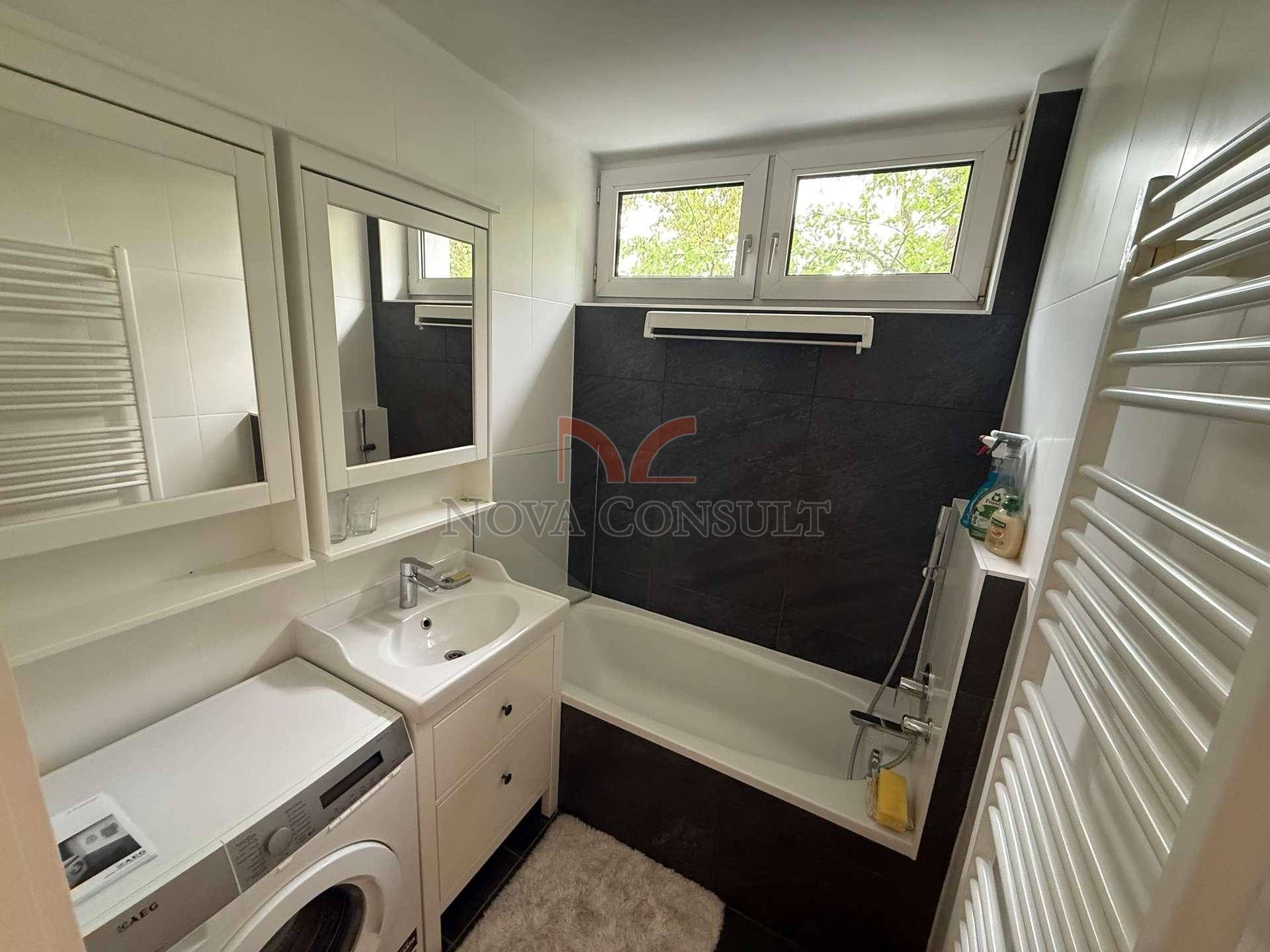 Modernes Badezimmer mit Badewanne, Waschbecken und Fenster, ausgestattet mit Waschmaschine.