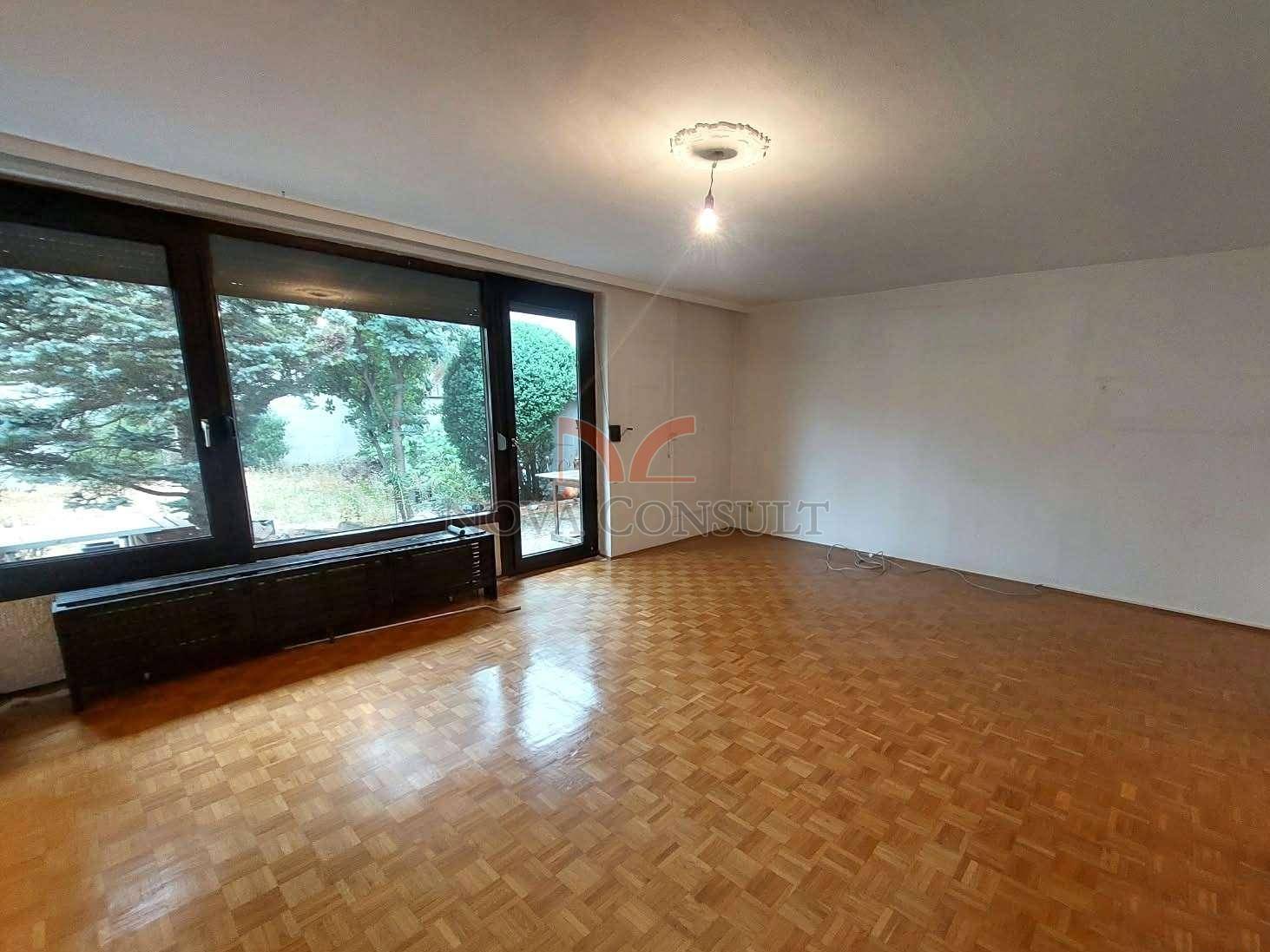 Geräumiges Wohnzimmer mit Parkettboden und großen Fenstern mit Zugang zum Garten.