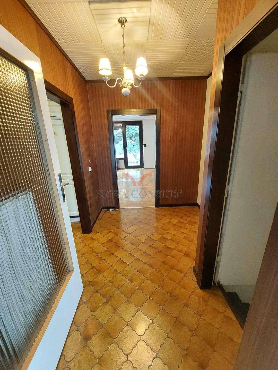 Langer Flur mit Holzvertäfelung und gemustertem Fliesenboden, der zu weiteren Räumen führt.