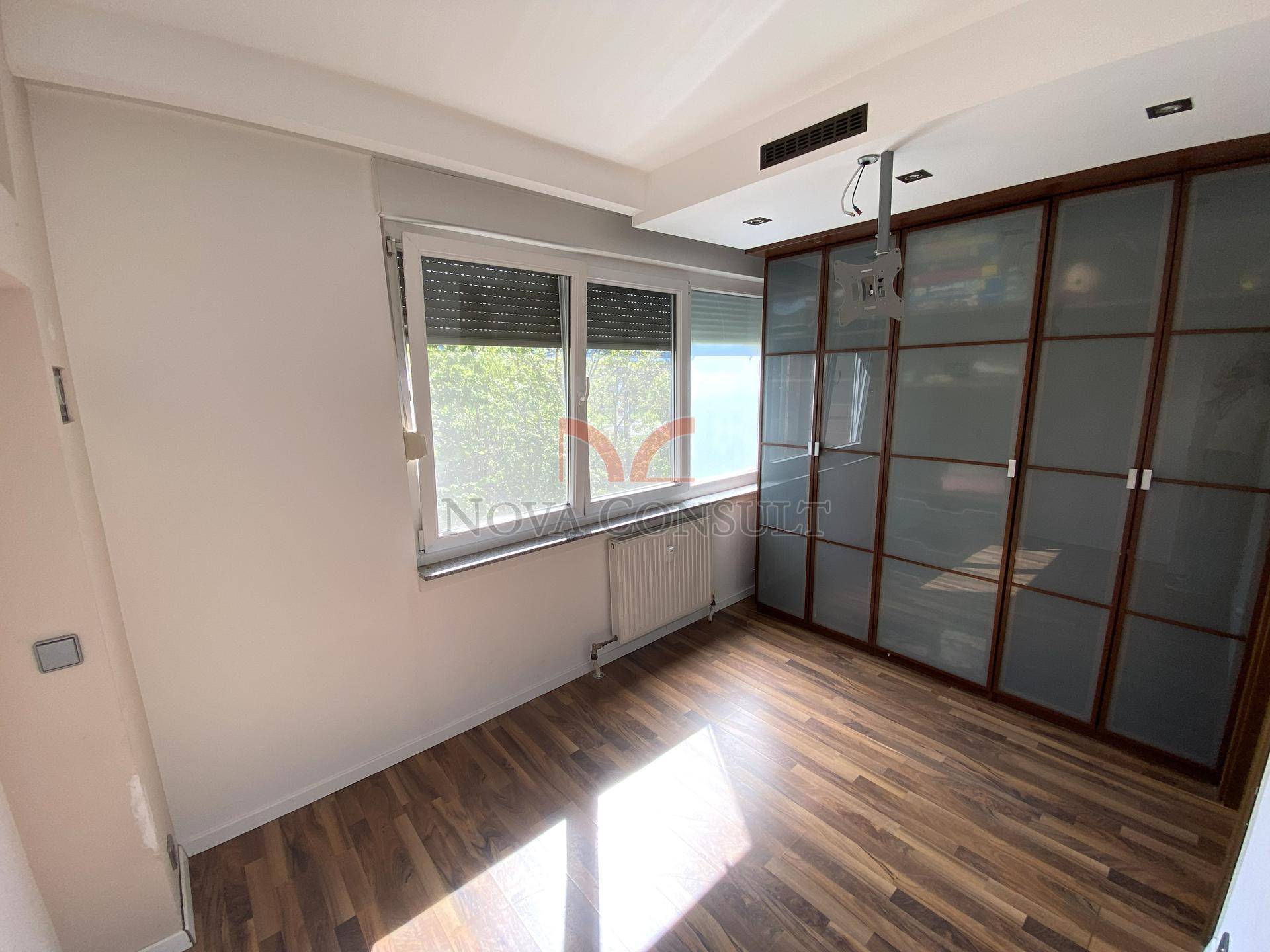Schlafzimmer mit Holzboden, Einbauschränken, Fenster und Klimaanlage.