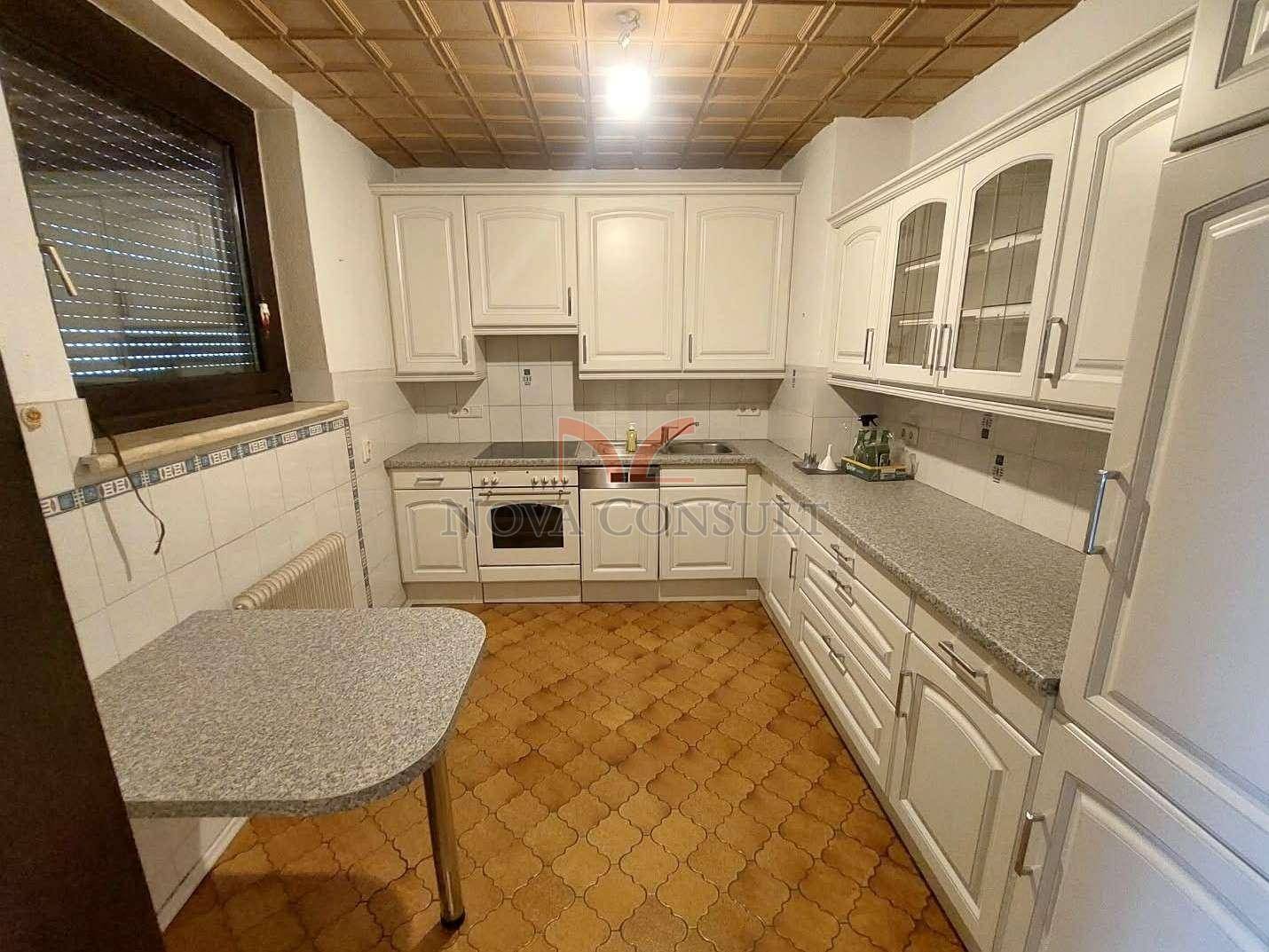Traditionelle Küche mit weißen Schränken, gemustertem Fliesenboden und einem Fenster.