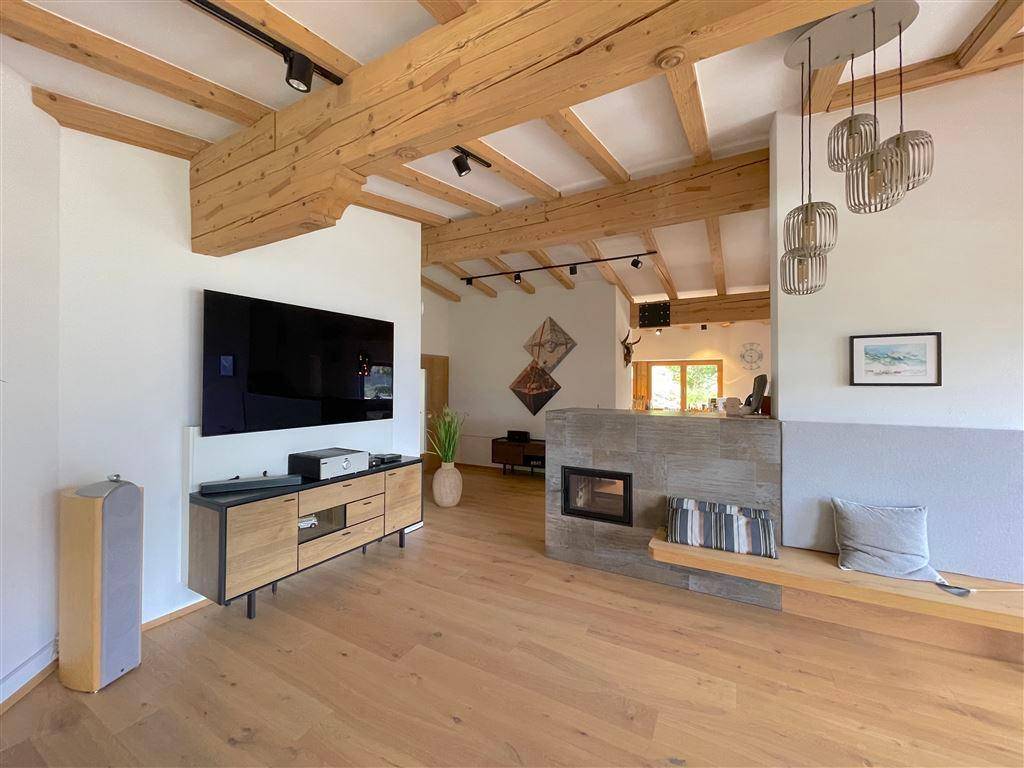 Geräumiges Wohnzimmer mit Holzboden, modernem Kamin und integriertem TV-Bereich.