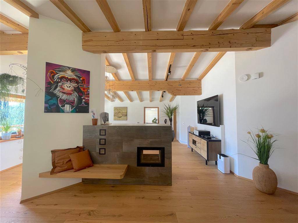 Offener Wohnbereich mit Holzboden, Kamin und moderner Einrichtung, die Gemütlichkeit ausstrahlt.