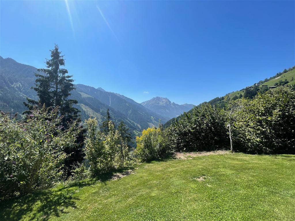 Gepflegter Gartenbereich mit Rasenfläche und weitem Blick auf die majestätische Berglandschaft.
