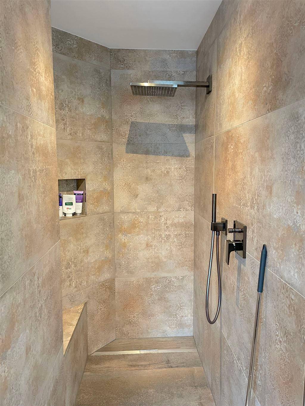 Moderne begehbare Dusche mit großformatigen Fliesen und Regenduschkopf für ein Spa-Erlebnis.