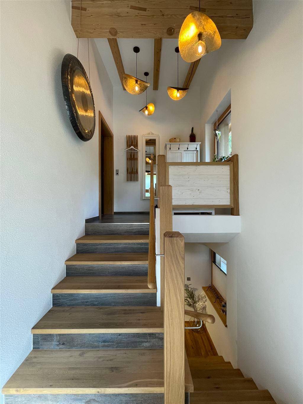 Heller Flur mit Holztreppe und sichtbaren Holzbalken, der verschiedene Ebenen des Hauses verbindet.