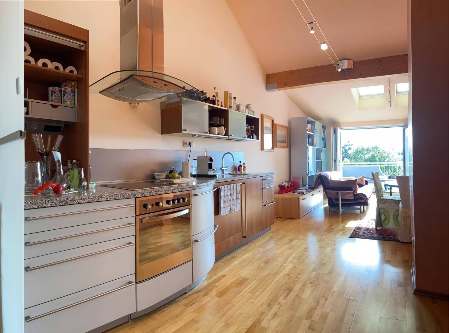 Offene Küche mit Essbereich und Wohnzimmer, Holzboden und Zugang zur Terrasse.