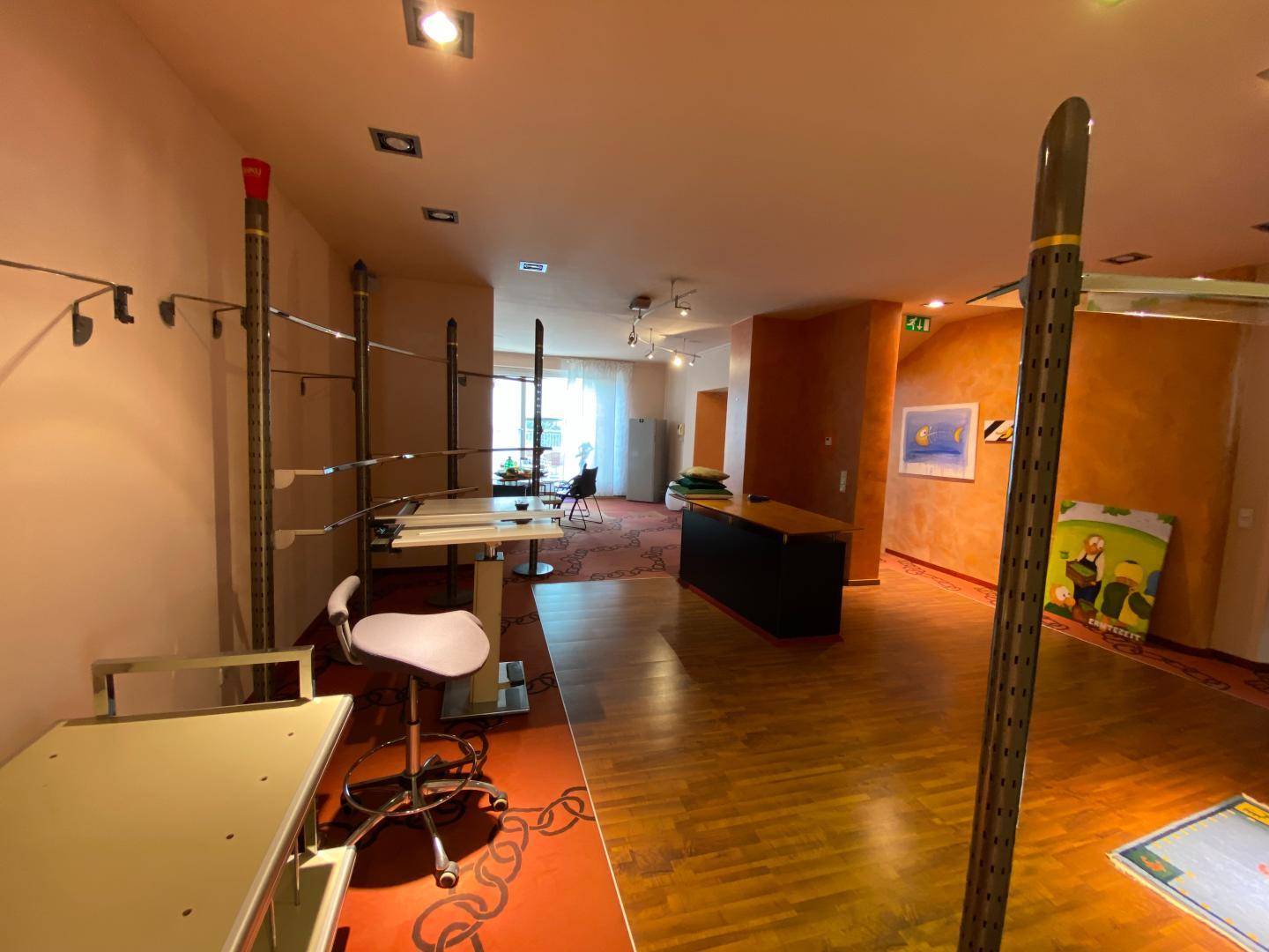 Offener Verkaufsbereich mit flexiblen Regalsystemen, Holzboden und farbigen Wänden.