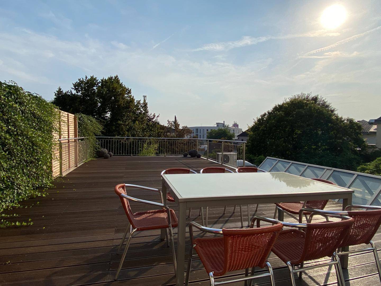 Große Dachterrasse mit Holzboden, Gartenmöbeln und weitem Blick über die Umgebung.