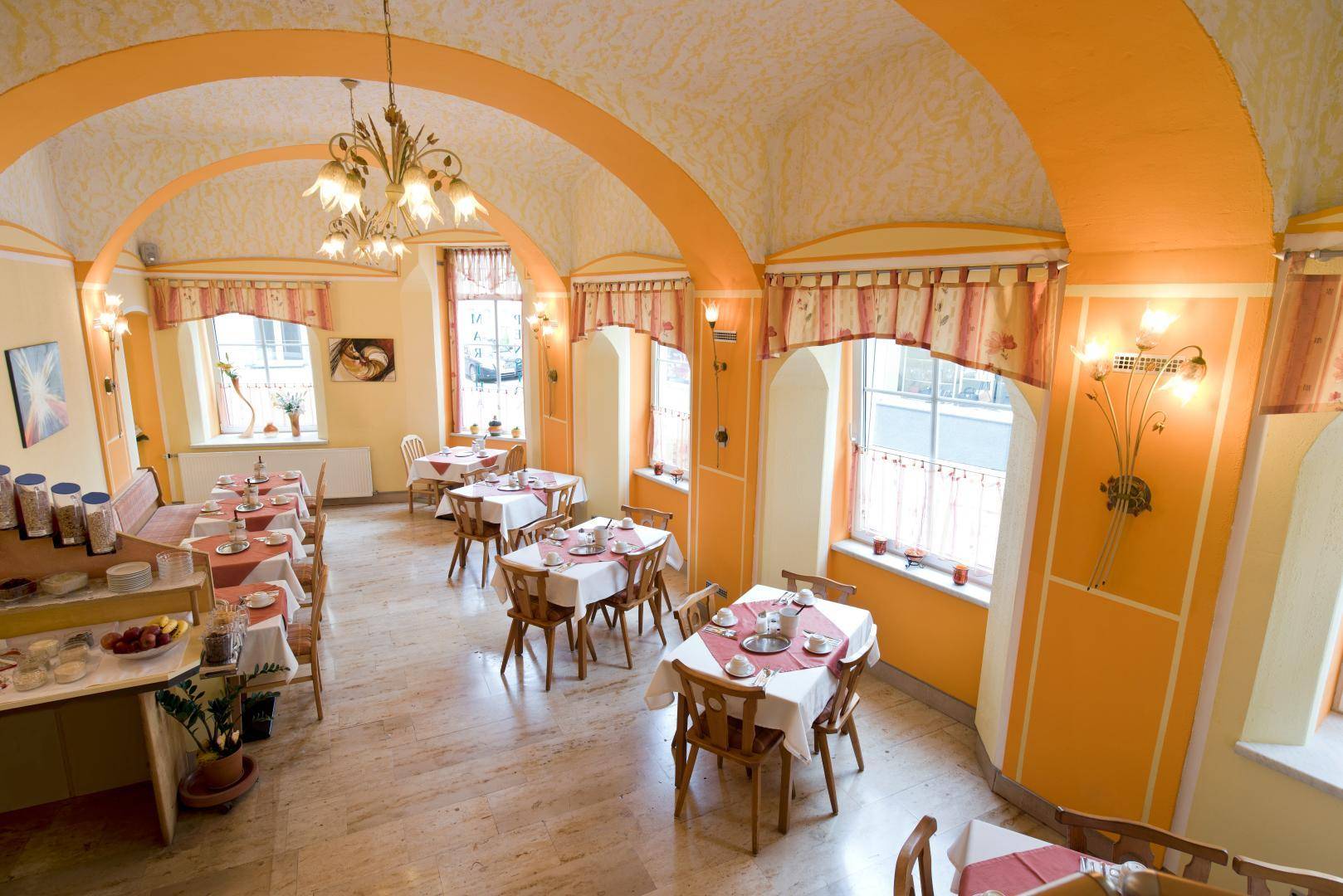 Gemütlicher Speisesaal mit orangefarbenen Gewölbedecken, Holztischen und traditioneller Einrichtung.