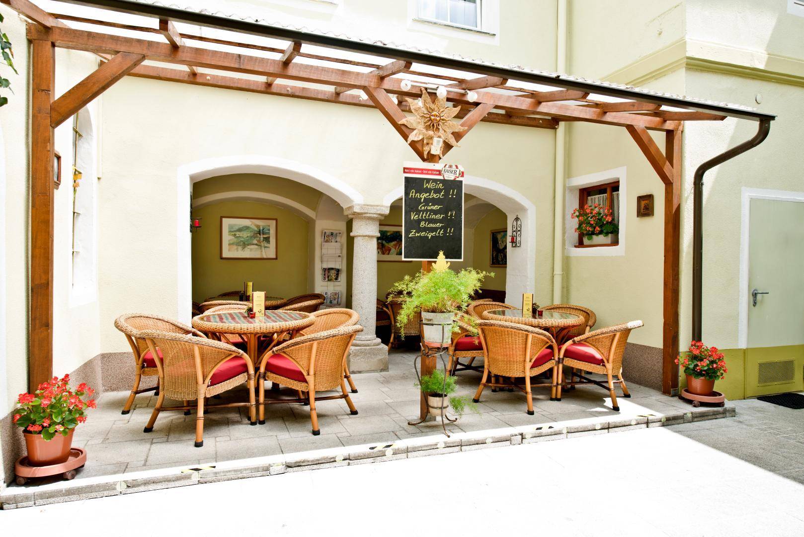 Gemütliche Außenterrasse mit Korbmöbeln unter einer Holzpergola, ideal für entspannte Stunden.
