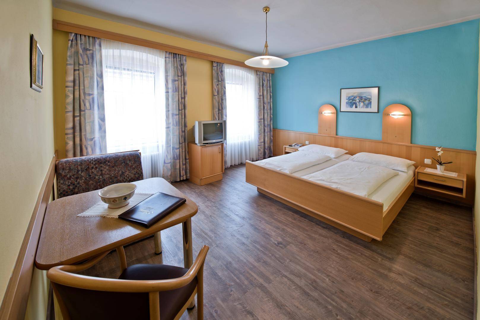 Geräumiges Schlafzimmer mit Doppelbett, Holzboden und einer blauen Akzentwand, hell und einladend.