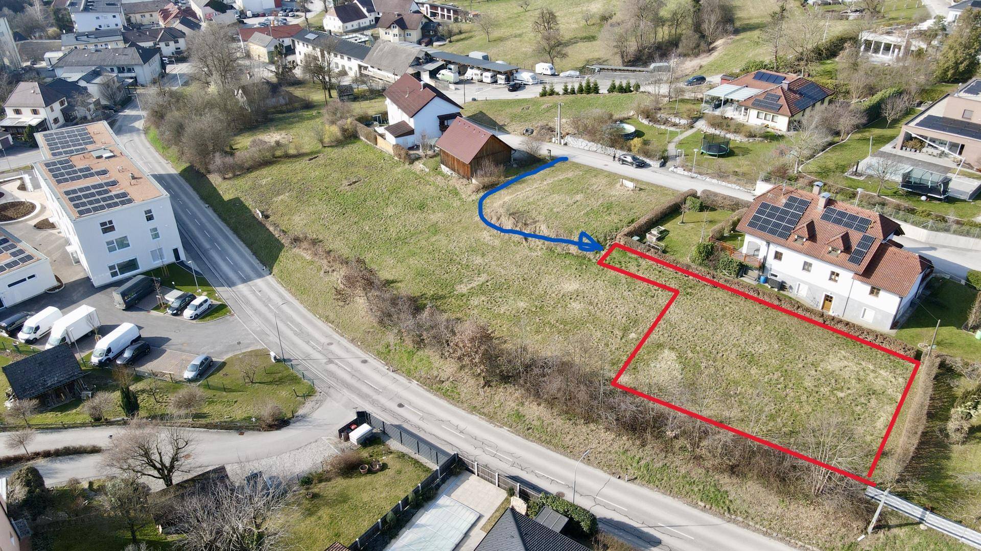 Luftaufnahme von Baugrundstücken und umliegenden Wohnhäusern mit Straßen und Grünflächen.
