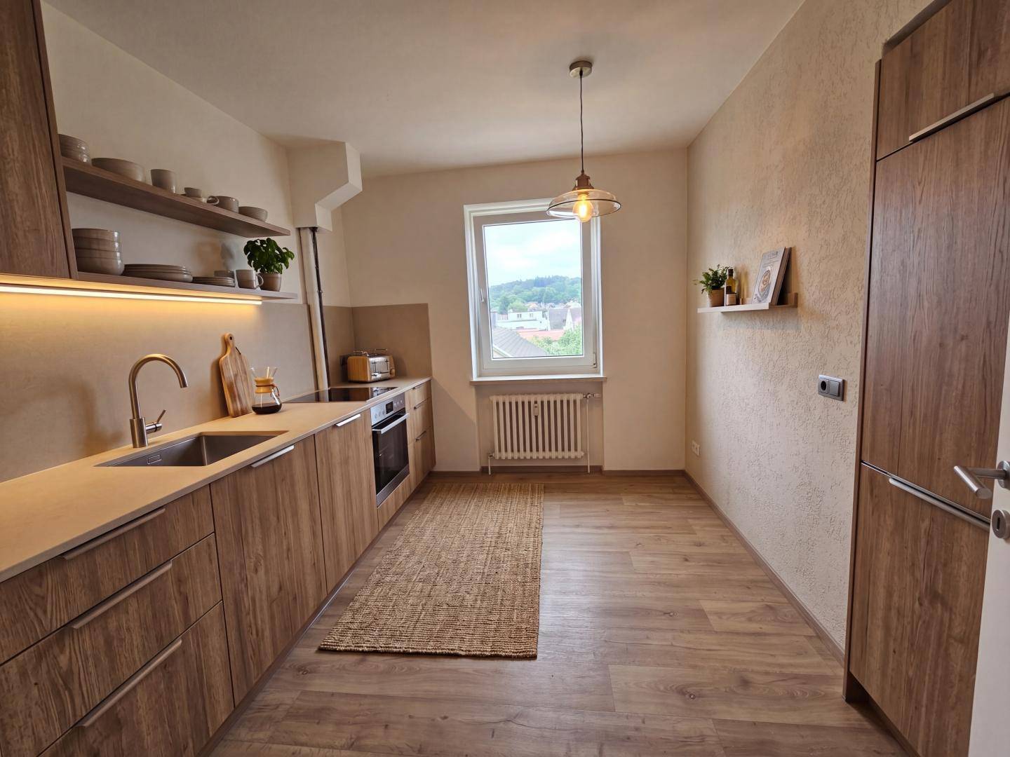 Moderne Küche mit Holzfronten, integrierten Geräten und Fenster mit Ausblick.