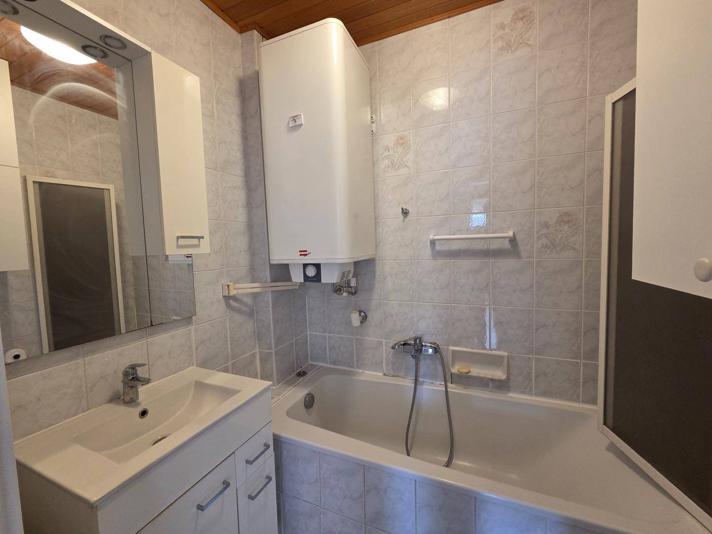 Funktionales Badezimmer mit hellblauen Fliesen, Badewanne und Waschbecken.