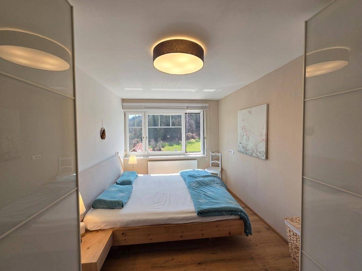 Modernes Schlafzimmer mit großem Bett, Einbauschränken und weitem Blick aus dem Fenster.