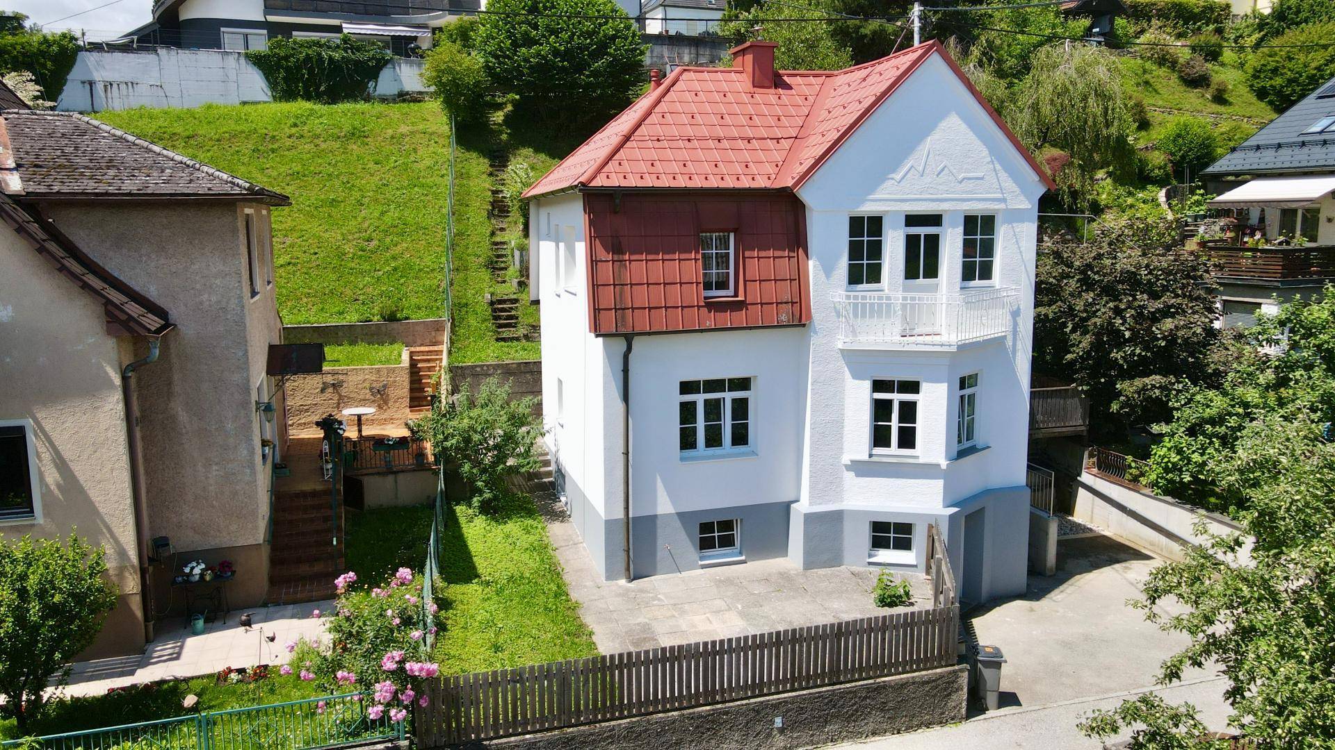 Ansicht des Hauses mit weißer Fassade, rotem Dach und einem kleinen Vorgartenbereich.