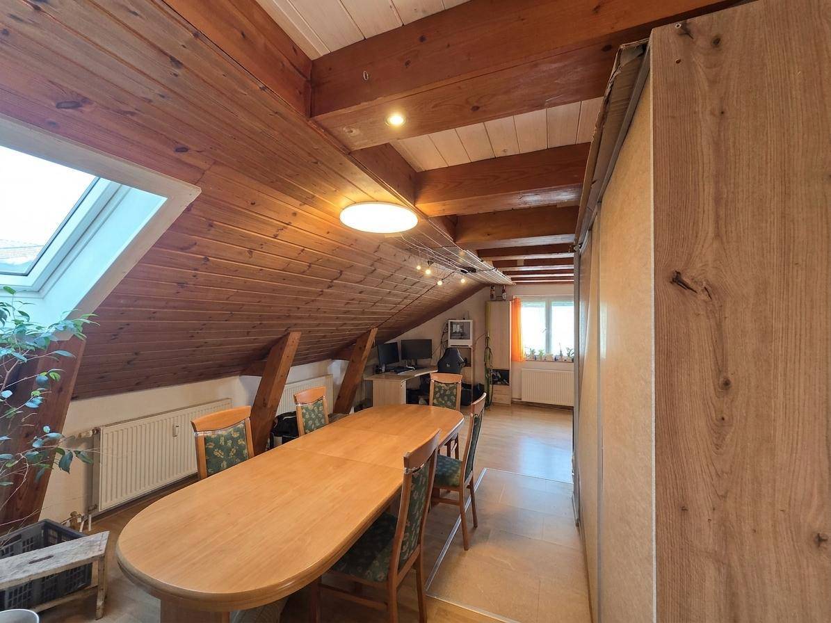 Geräumiger Essbereich im Dachgeschoss mit Holzbalkendecke und großem Esstisch.