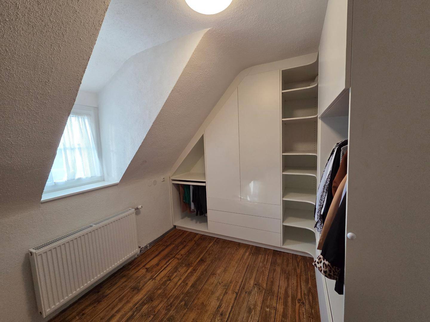 Praktischer begehbarer Kleiderschrank im Dachgeschoss mit maßgefertigten Einbauschränken.