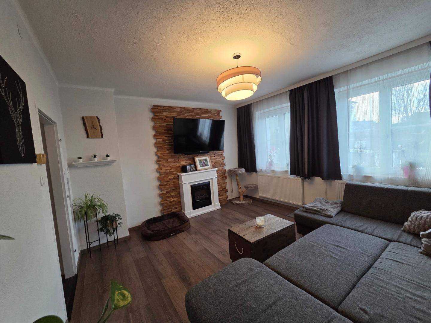 Gemütliches Wohnzimmer mit Holzboden, dekorativem Kamin und großem Ecksofa.