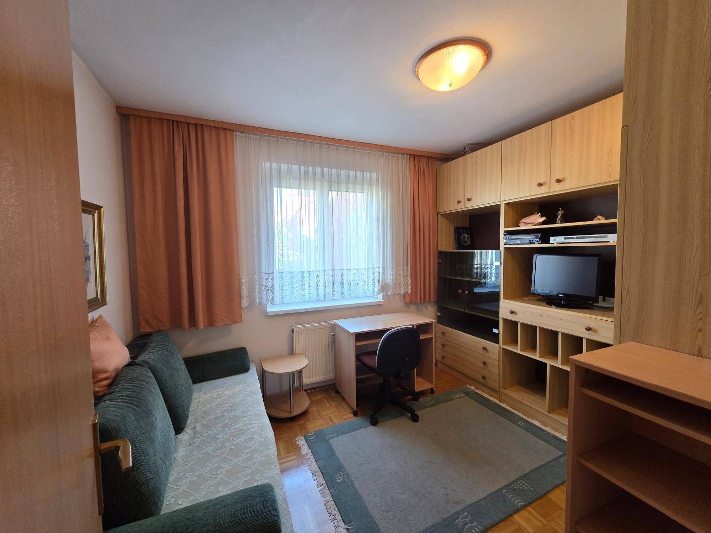 Kleines Zimmer mit Schreibtisch, Sofa und Stauraum, ideal als Büro oder Gästezimmer nutzbar.