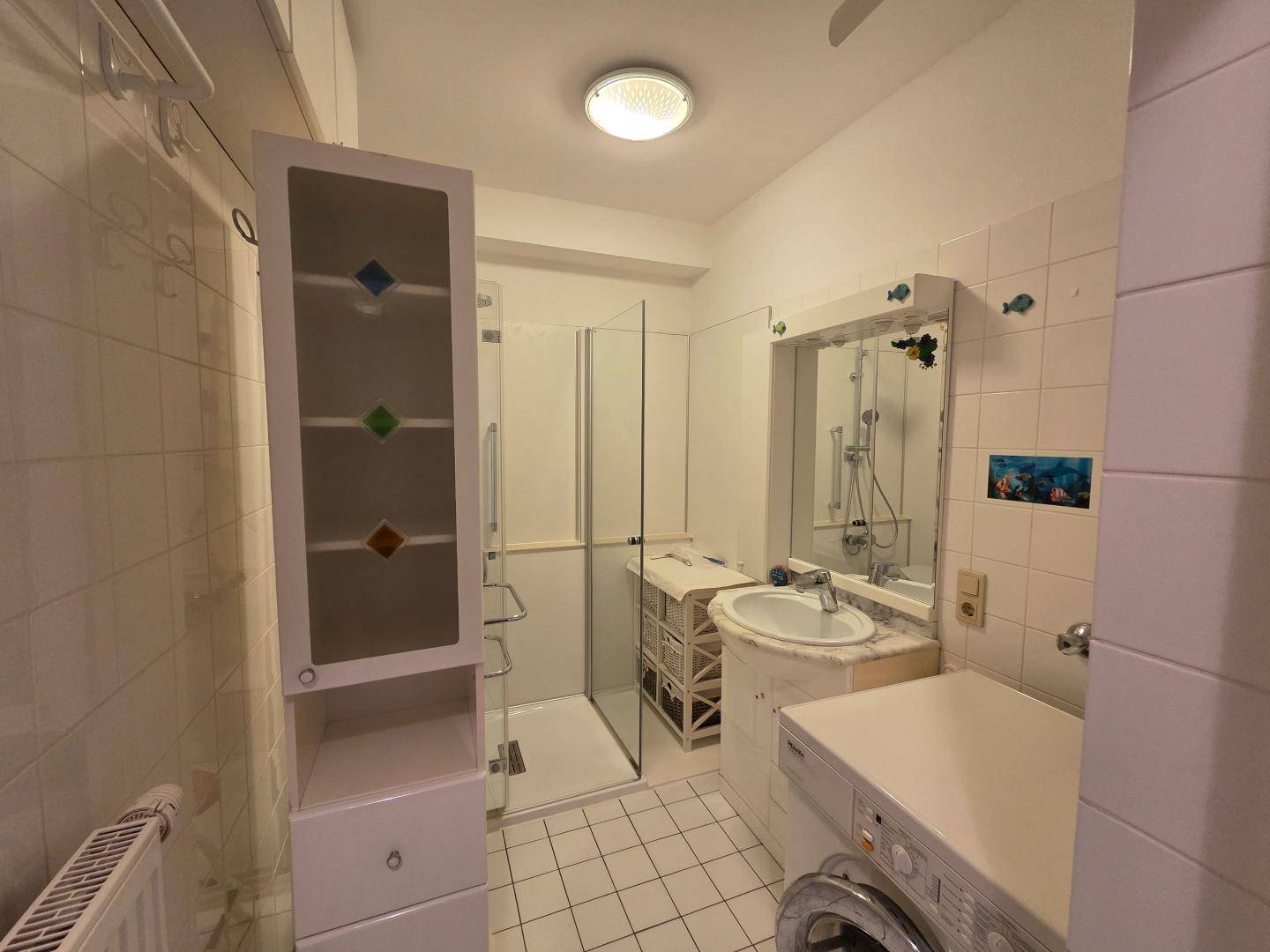 Badezimmer mit Dusche, Waschbecken, Waschmaschine und weißen Fliesen im traditionellen Stil.