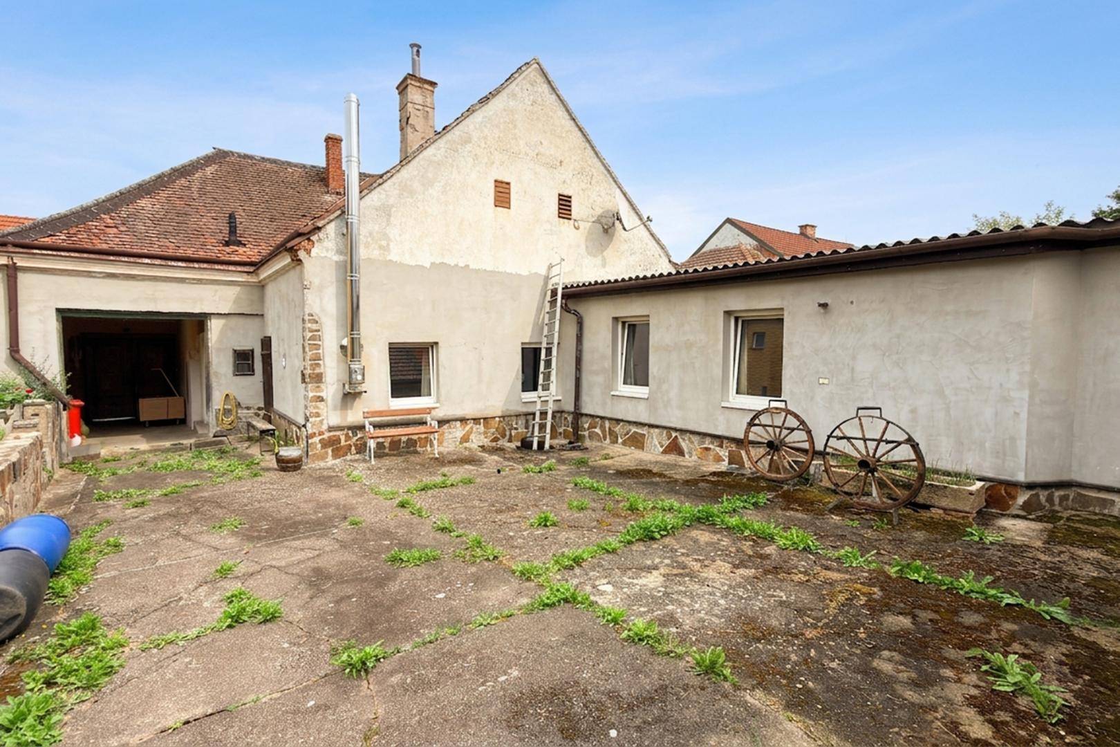 Hinterhof mit großer Betonfläche, die als Terrasse genutzt werden kann, und Blick auf die Rückseite des Hauses.