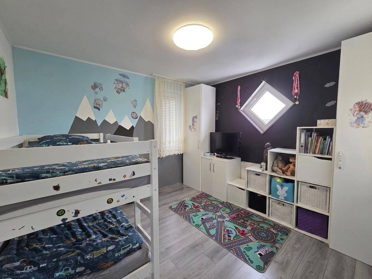 Kinderzimmer mit Etagenbetten, kreativer Wandgestaltung und Spielteppich.