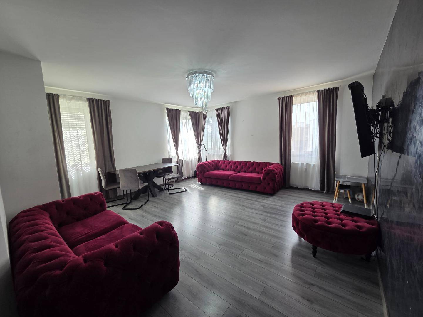 Geräumiger Wohn- und Essbereich mit auffälligen roten Samtsofas und modernem Kronleuchter.