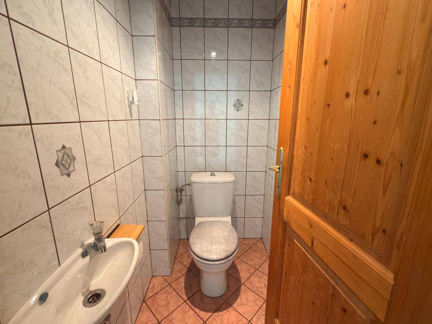 Separate Toilette mit rosa-weißen Fliesen, WC und Bidet.
