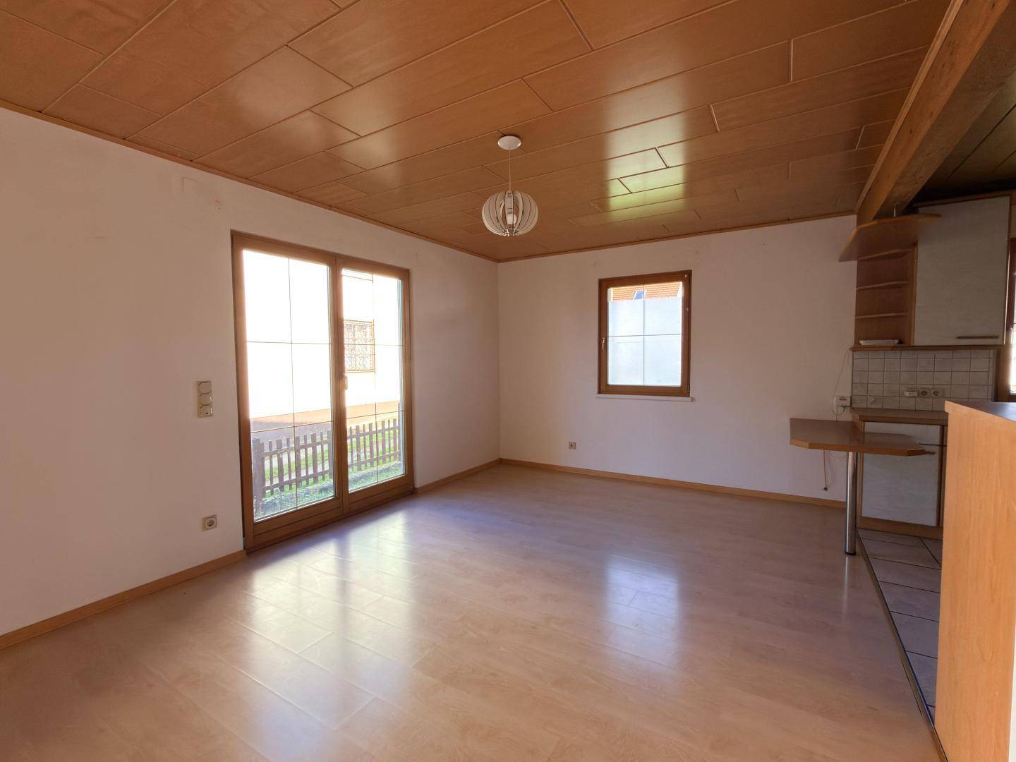 Heller Wohn-Essbereich mit Holzdecke, Parkettboden und Zugang zum Außenbereich.