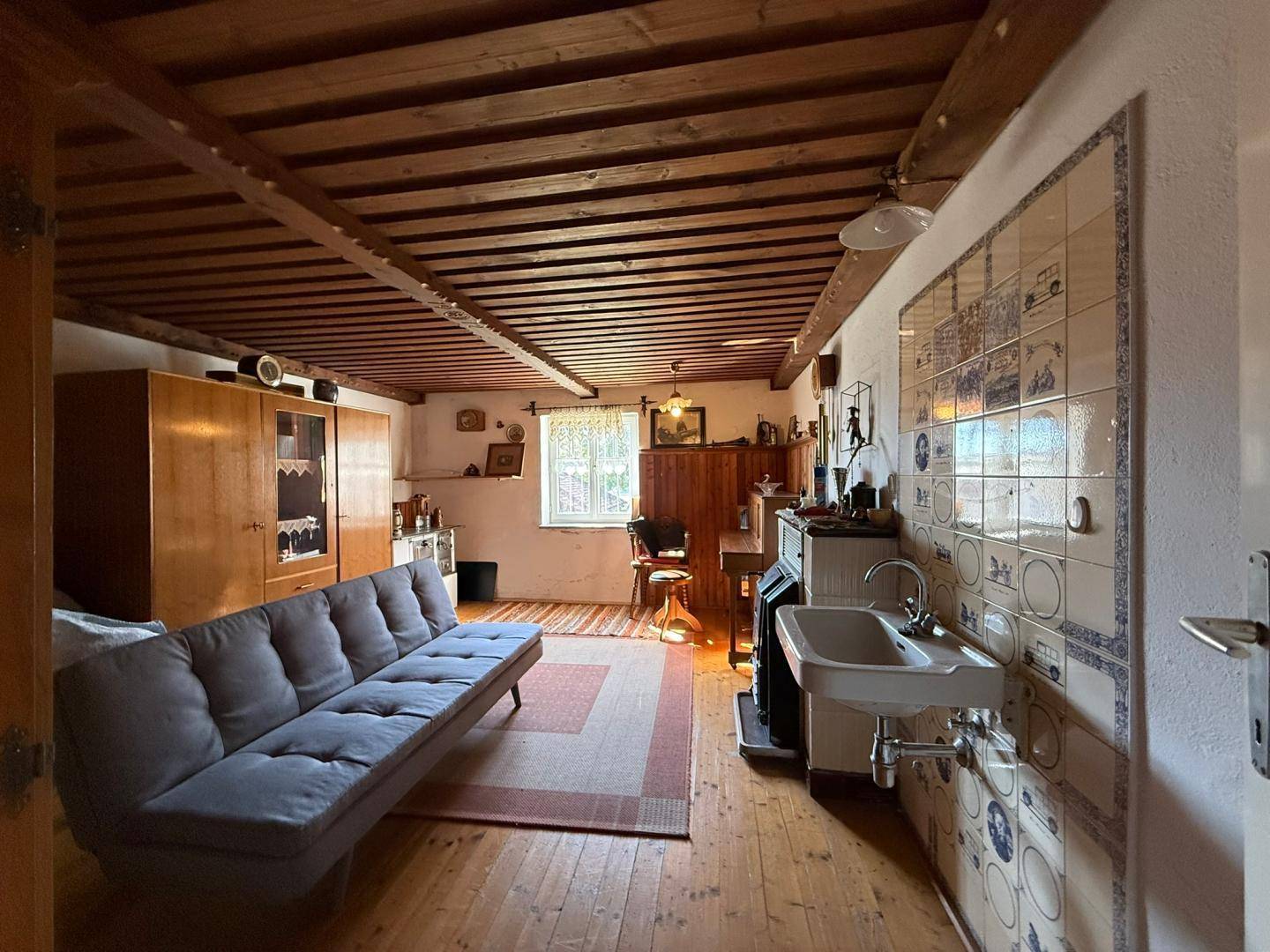 Rustikaler Wohnraum mit Holzbalkendecke, Sofa und traditionellen Elementen.
