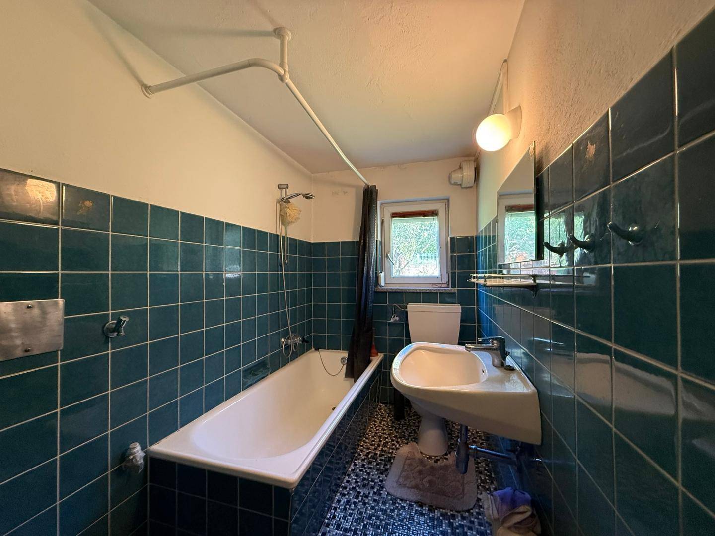 Badezimmer mit blauen Fliesen, Badewanne und Waschbecken im Retro-Stil.
