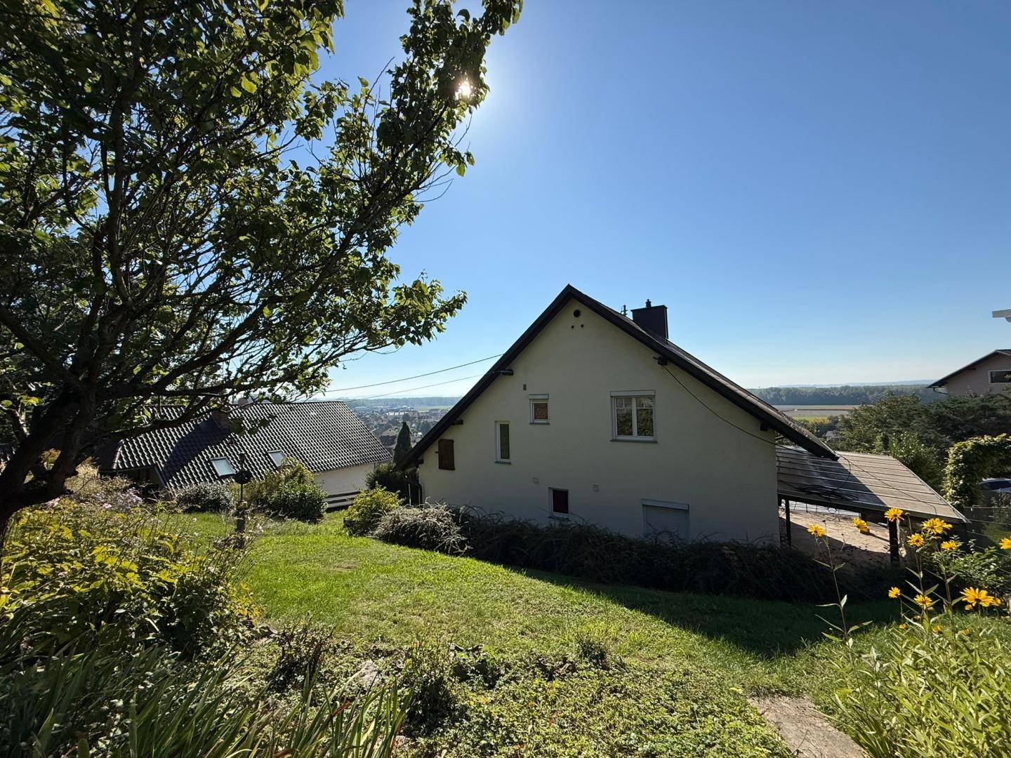 Garten mit Bäumen und Blick auf das Haus und die umliegende Landschaft.