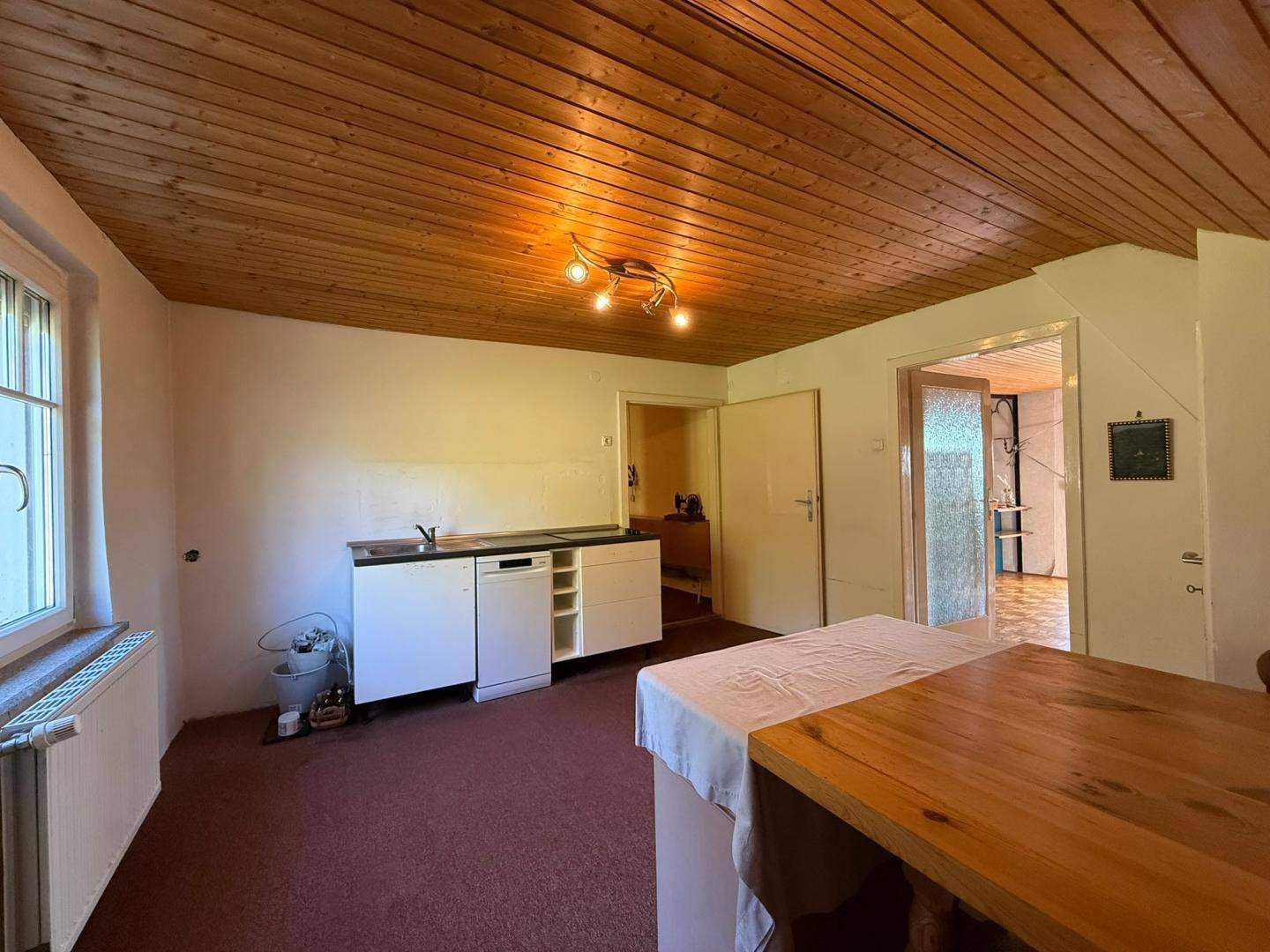 Einfache Küche mit Holzdecke, Spüle und Platz für einen Essbereich.